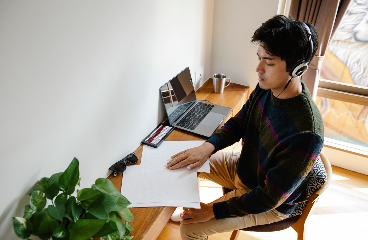 A man wearing headphones, concentrating while working at a desk.