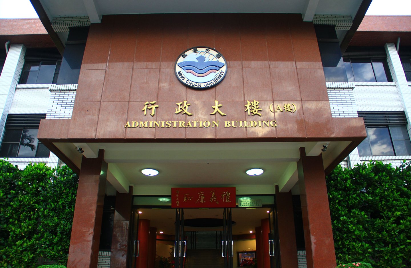 The administration building entrance at Ming Chuan University in Taiwan, with bilingual Chinese and English signage.