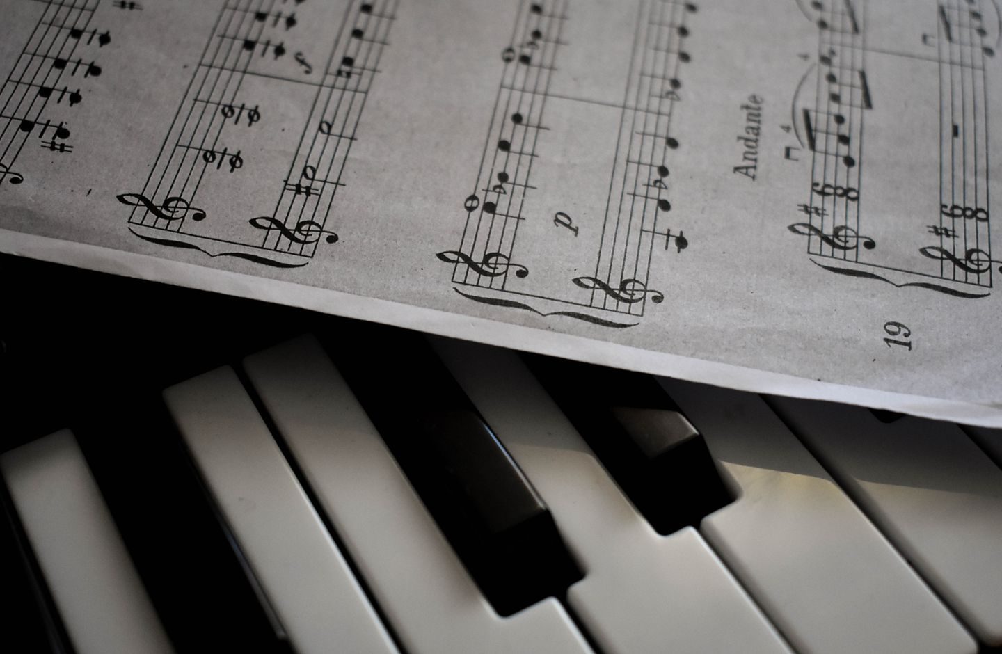Sheet music resting on piano keys, evoking a short melodic phrase.