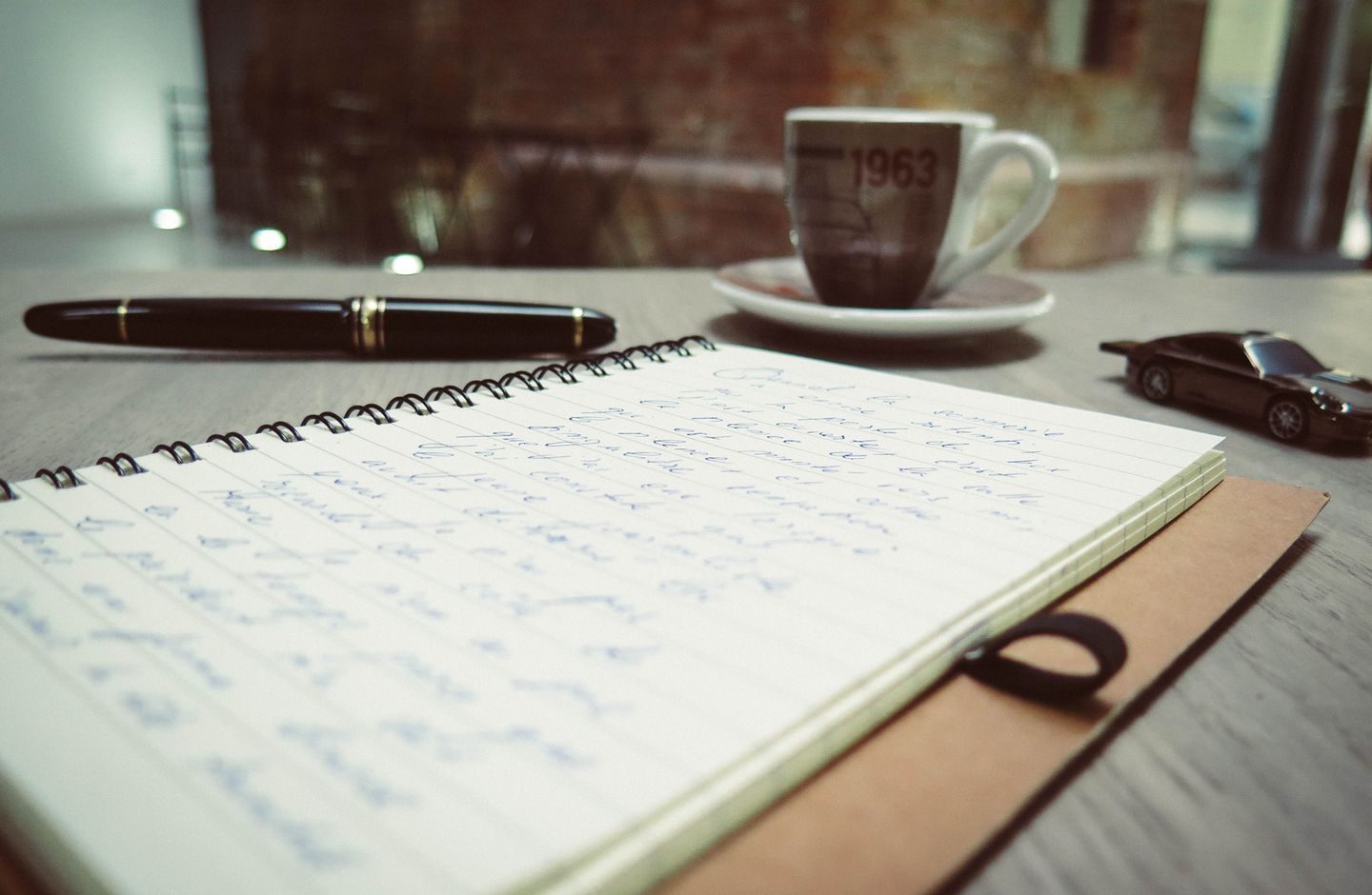 A cozy workspace with a notebook, pen, and a cup of coffee.