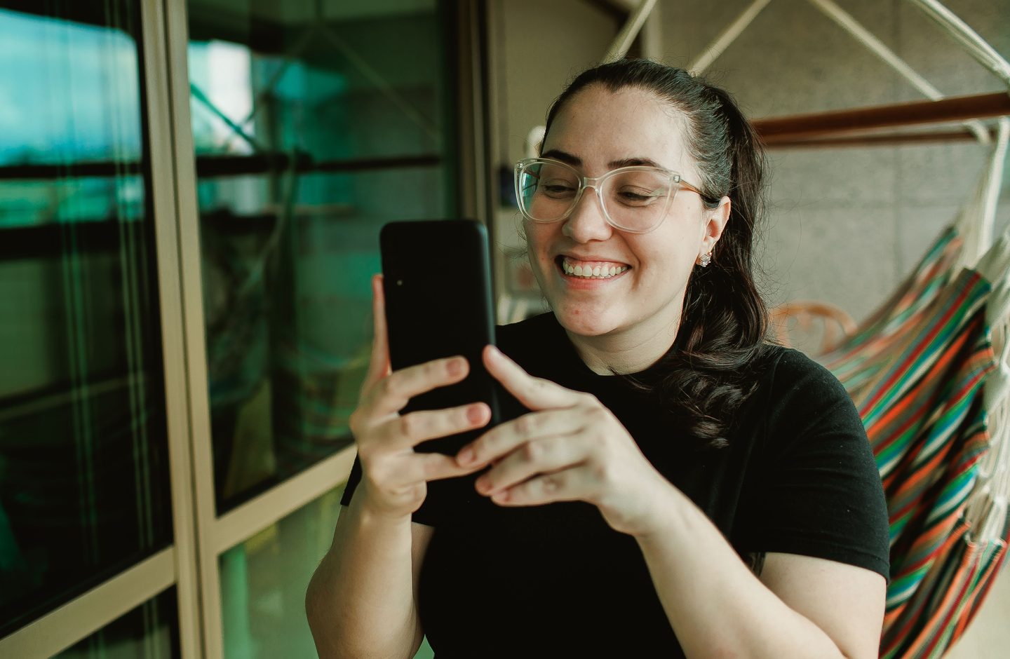 A young woman smiling while looking at an app on her smartphone.