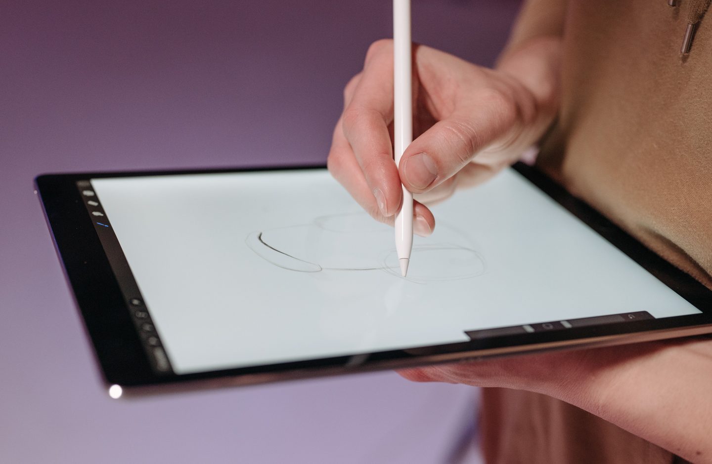 A hand drawing on a tablet screen with a white stylus.