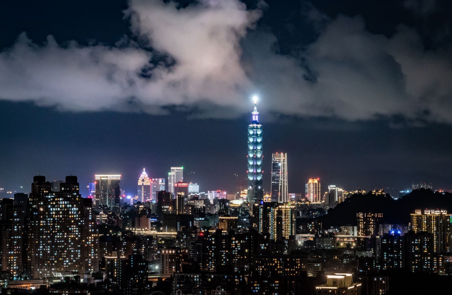 Taipei's skyline at night with Taipei 101 illuminated above the city.