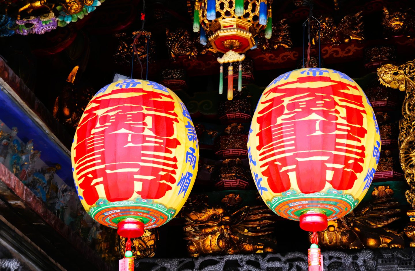 Traditional Chinese characters painted on red-and-gold lanterns hanging inside a Taiwanese temple.