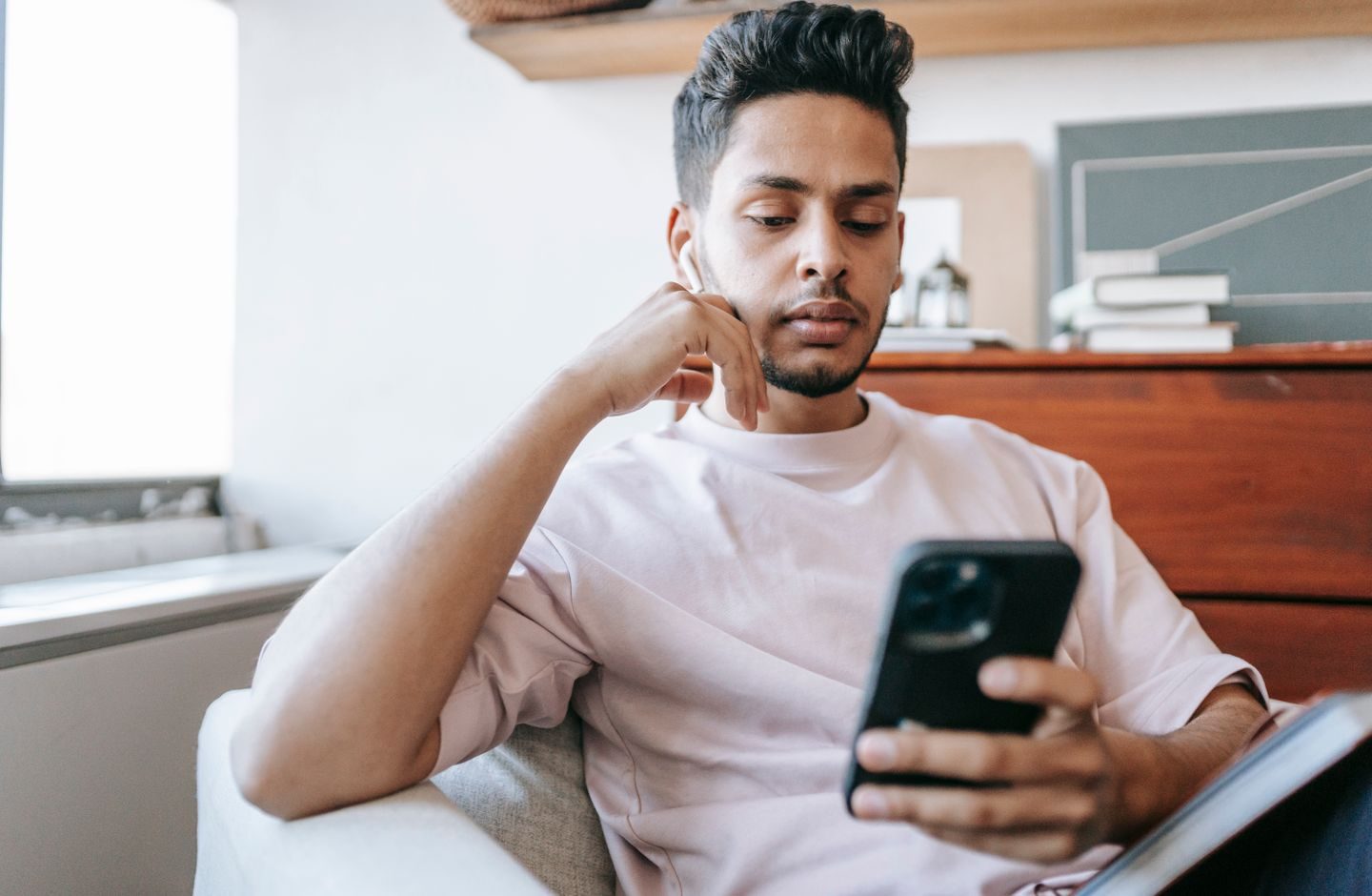 A thoughtful person looking at their smartphone, weighing what they're reading.