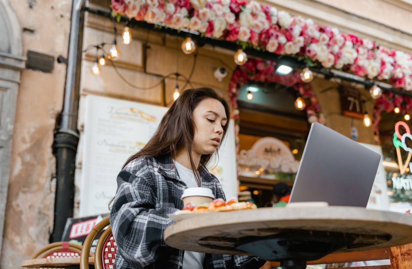 A woman at a café table, working on a laptop.